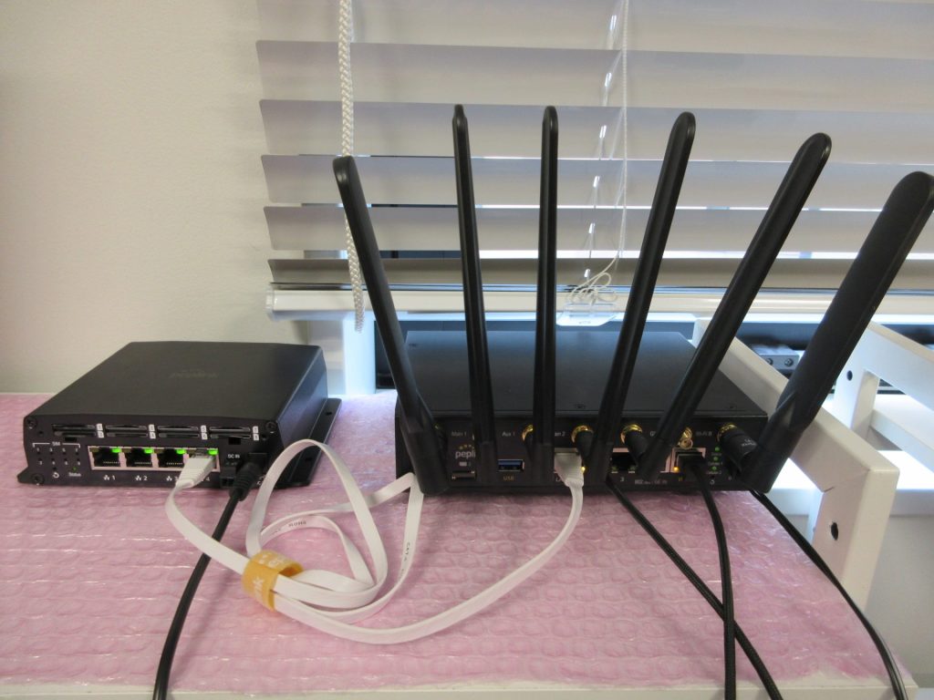 SIM InjectorとPeplink MAX BR2ルーターをLANケーブルで接続した写真。5本のアンテナとLANポートが確認できる。